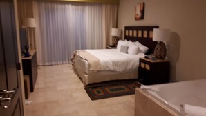 Ein Hotelzimmer mit einem Bett, Nachttischen, einer Lampe, einem Schreibtisch und einem Badezimmer mit einer Badewanne.