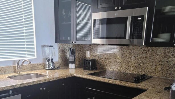 Eine moderne Küche mit Granit Arbeitsplatten, einem eingebauten Geschirrspüler, einer Mikrowelle und einem Toaster.