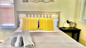 A neatly made bed with a patterned bedspread, two pillows, and rolled towels. - Lovely South Austin Condo. All Essentials Included (Austin)