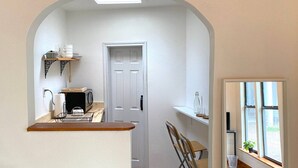 A compact kitchen with a microwave, kettle, and shelves. - East Austin Garden Cottage |  Sweet & Private (Austin)