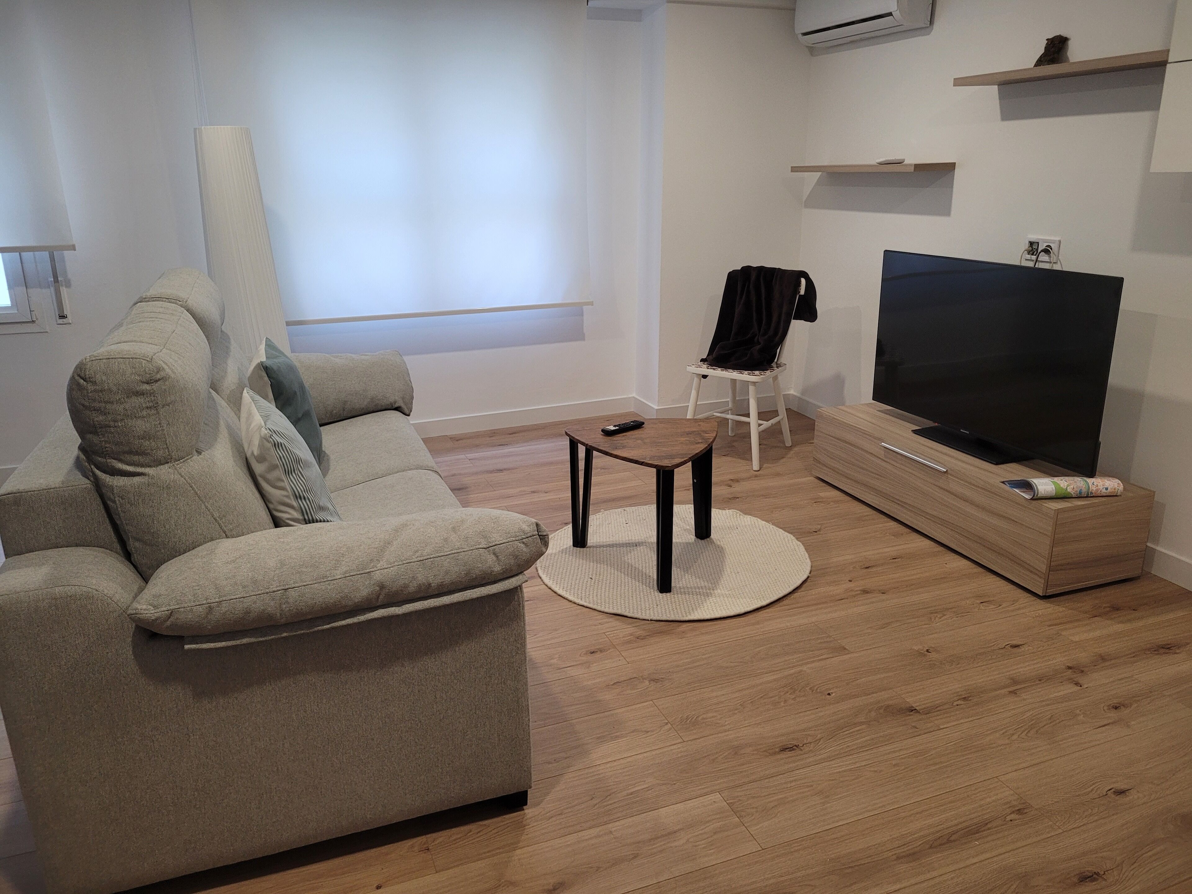 Een moderne woonkamer met een bank, een salontafel, een televisie en een houten kast.