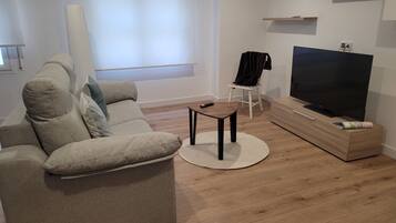Een moderne woonkamer met een bank, een salontafel, een televisie en een houten kast.