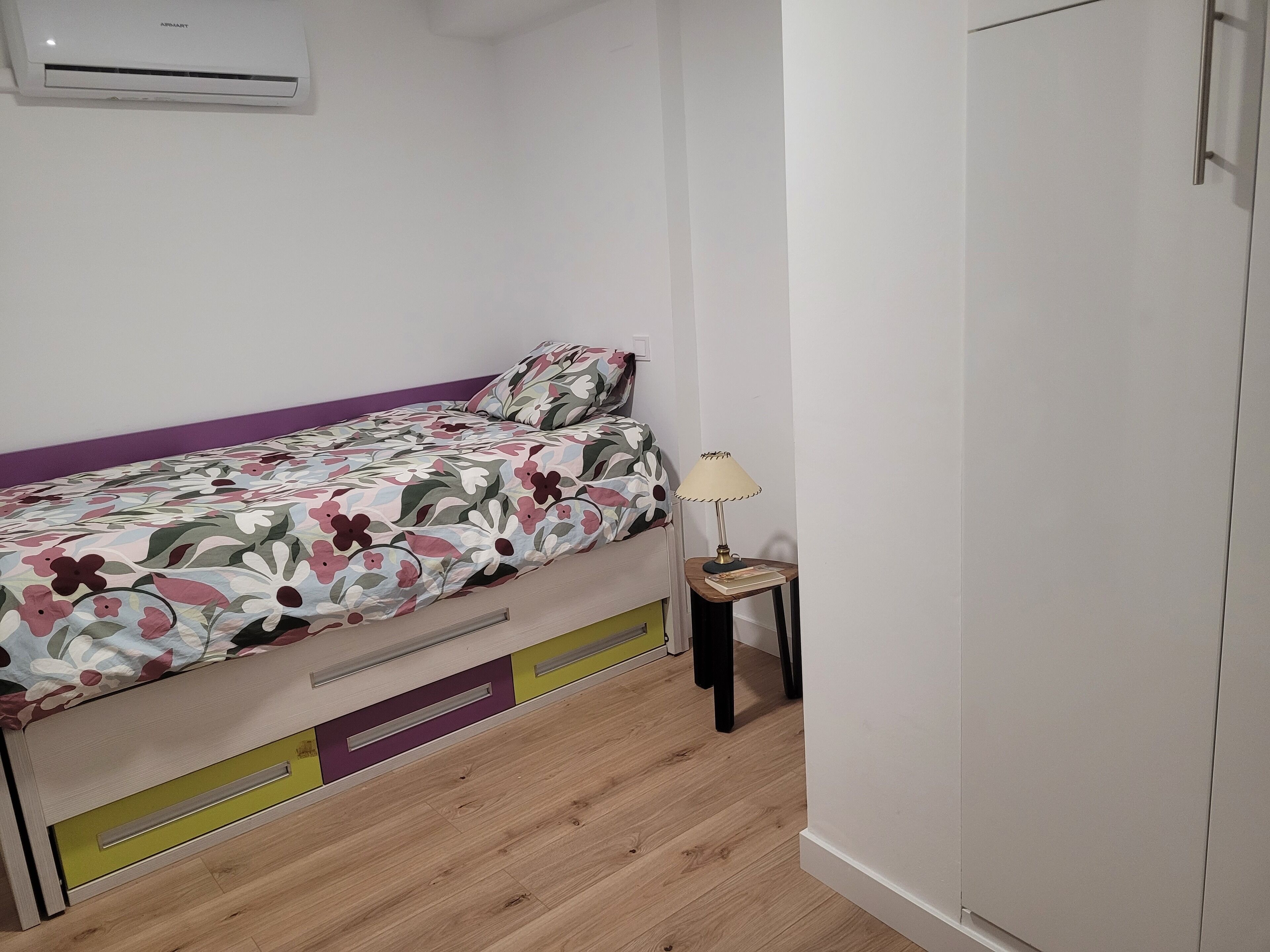 Une chambre à coucher avec un lit, une table de chevet avec une lampe et une armoire.