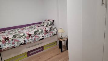 Une chambre à coucher avec un lit, une table de chevet avec une lampe et une armoire.