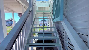 A staircase leading to a covered area with a view of a house and a clear sky. - Bolivar Beachside Getaway (Crystal Beach)