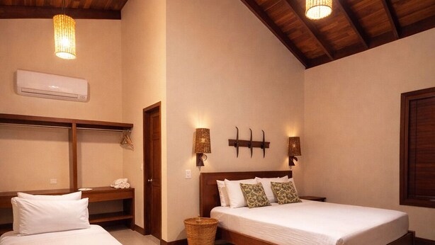 A room with two beds, wooden beams on the ceiling, wall-mounted sconces, and a hanging light fixture. - Pousada Rancho Paraiso (Porto de Pedras)