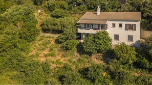 Ein zweistöckiges Haus mit Balkon, umgeben von dichter Vegetation.