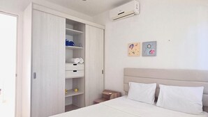 Een slaapkamer met een bed, een kledingkast, een nachtkastje en een airconditioning.