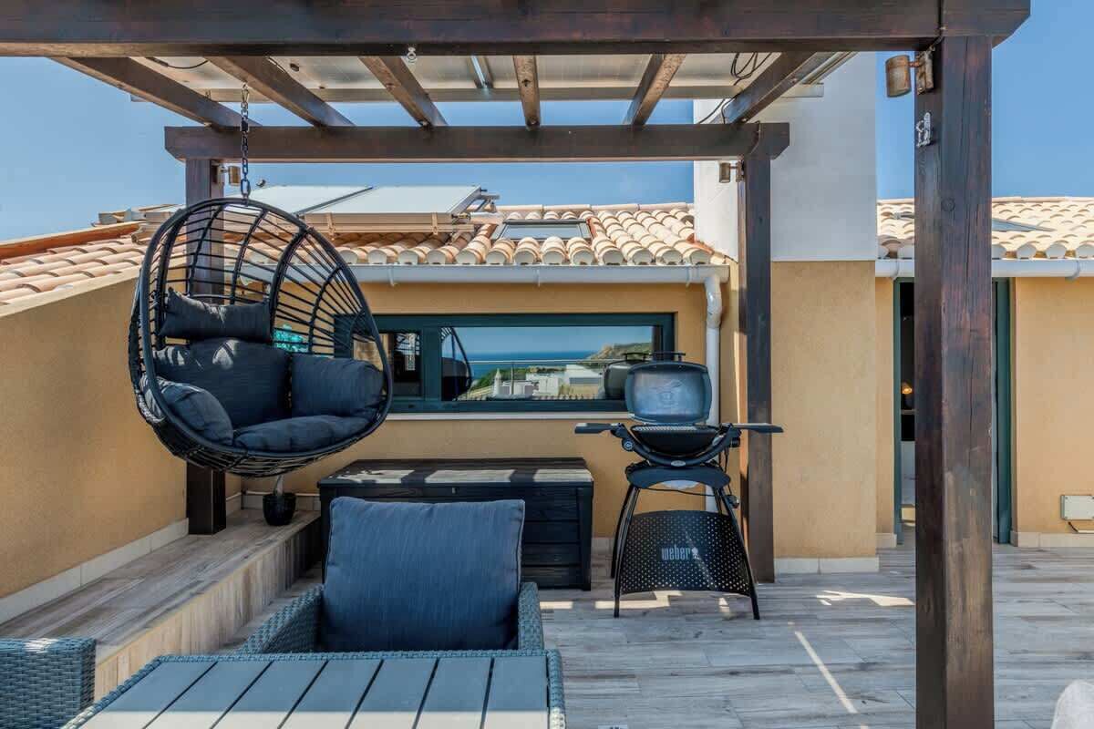 Eine Dachterrasse mit Hängestuhl, kleinem Tisch und Grill.