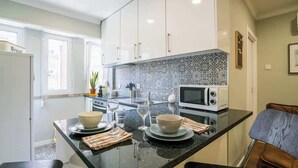 Et moderne køkken med hvide skabe, en sort bordplade og et mønstret backsplash.