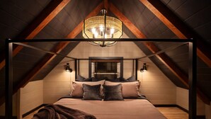 Une chambre à coucher avec un plafond voûté, un lit doté de nombreux oreillers et deux lampes fixées au mur.