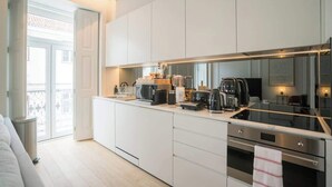 Eine moderne Küche mit weißen Schränken, einer Kochinsel mit Glasplatte und Edelstahlgeräten.