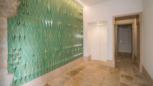 Ein Flur mit grüner geometrischer Wand, einer weißen Tür und Steinböden.