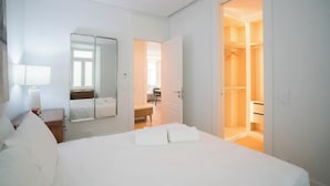 Ein Hotelzimmer mit einem Bett, einem Nachttisch, einem Spiegel und einem offenen Kleiderschrank.
