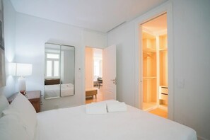 Ein Hotelzimmer mit einem Bett, einem Nachttisch, einem Spiegel und einem offenen Kleiderschrank.