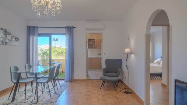 A modern living room with a dining area, a chandelier, and a view of the outdoors. - Casa Rocha Portimao with Terrace (Portimão)