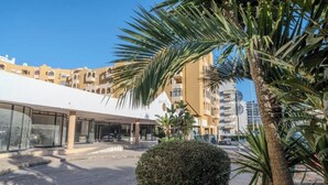 A modern building with a flat roof and large windows, surrounded by palm trees and a well-maintained garden. - Casa Rocha Portimao with Terrace (Portimão)