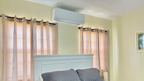 A bedroom with a bed, curtains, an air conditioner, and a bedside lamp. - Central & Secure Stay - Minutes from Town, Airport and Stadium (Osbourn)