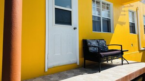 A yellow building with a white door and windows, a bench, and a tiled floor. - Central & Secure Stay - Minutes from Town, Airport and Stadium (Osbourn)