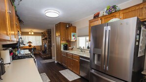 Una cocina con armarios de madera, un refrigerador de acero inoxidable y una encimera de mármol.