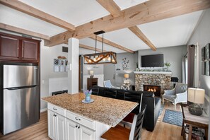 A modern kitchen with a central island, built-in appliances, and a stone fireplace. - True Ski-In/Ski-Out at Sugar Mtn (Bee Branch #1) (Sugar Mountain)