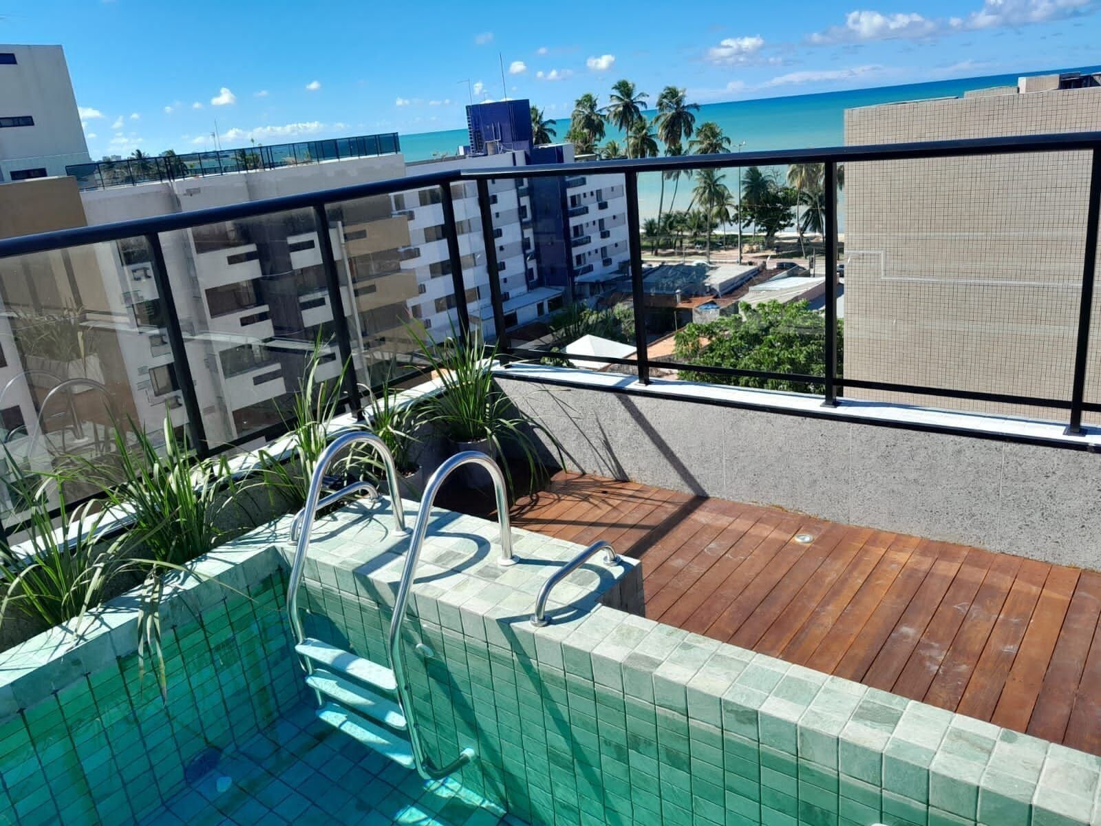 A rooftop pool with a view of the ocean and palm trees.