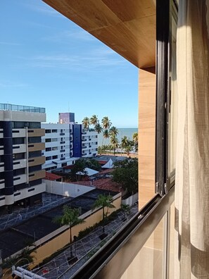 A view from a window overlooking a cityscape with buildings, palm trees, and a clear sky. - Flat Cabo Branco Aurea 50m do mar 601 (João Pessoa)