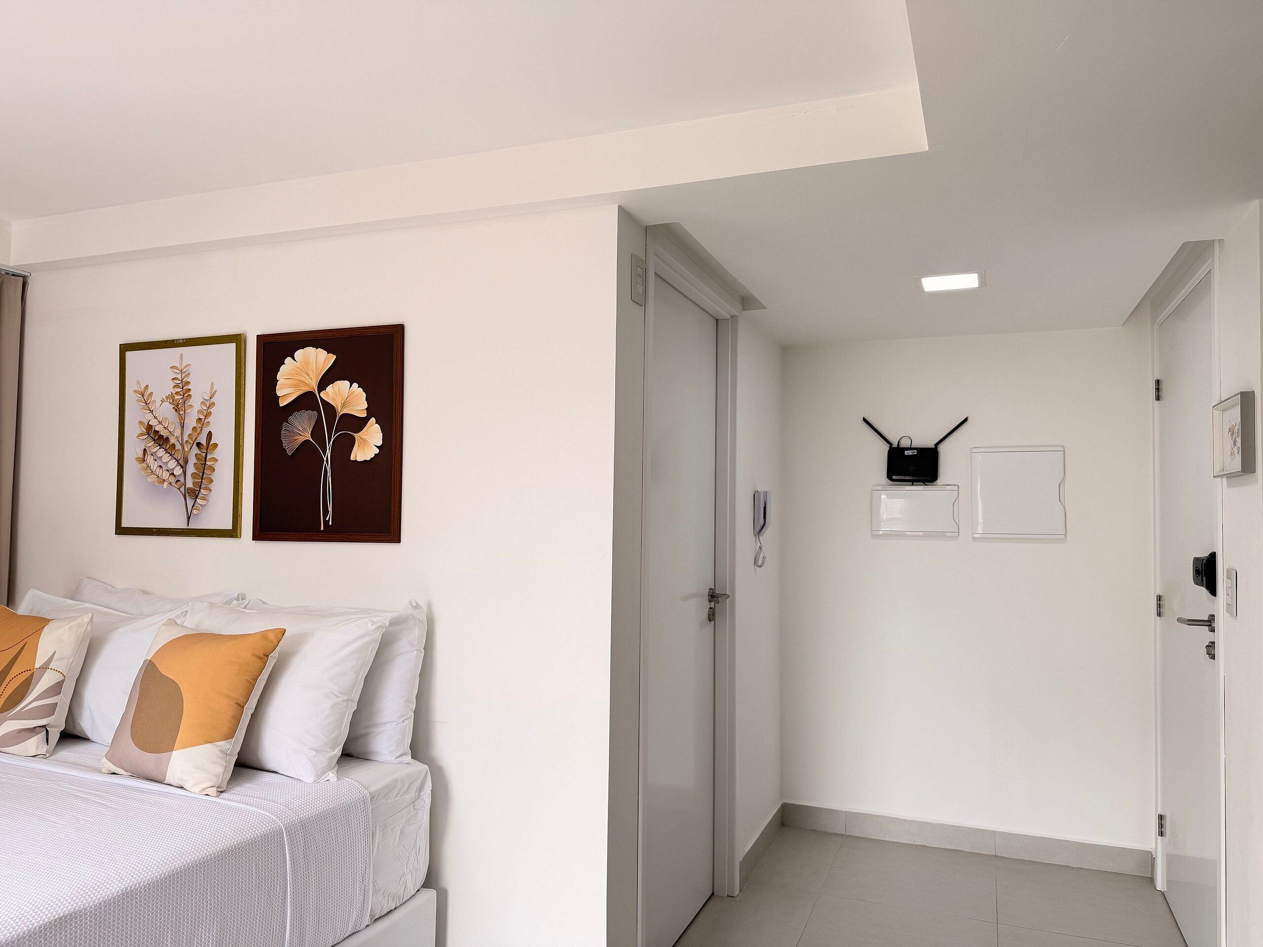 A hotel room with a bed, a door, and a hallway leading to another room.