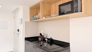 A compact kitchen with a microwave, sink, and cabinets.