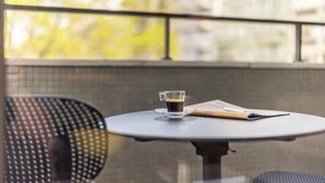 Une table ronde avec une tasse de café en verre, un menu et une chaise.