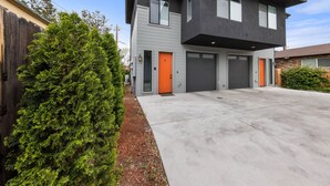 A modern two-story house with a garage, a well-maintained lawn, and a large evergreen tree. - Modern Midtown Oasis: Mountain Views & Walkable Vibes (Reno)