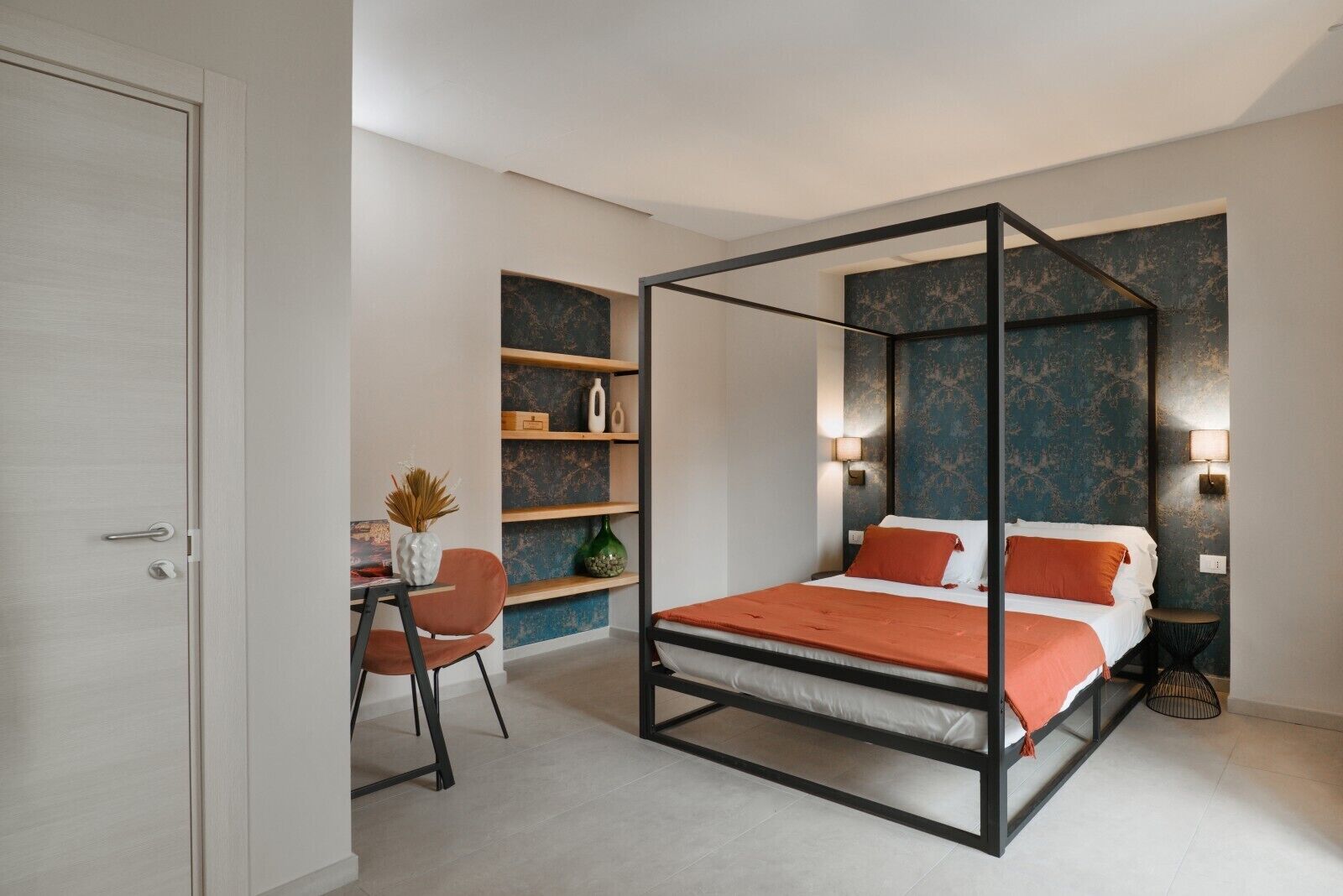 Ein modernes Schlafzimmer mit einem Himmelbett, einem Schreibtisch mit Stuhl und Regalen mit Dekoration.