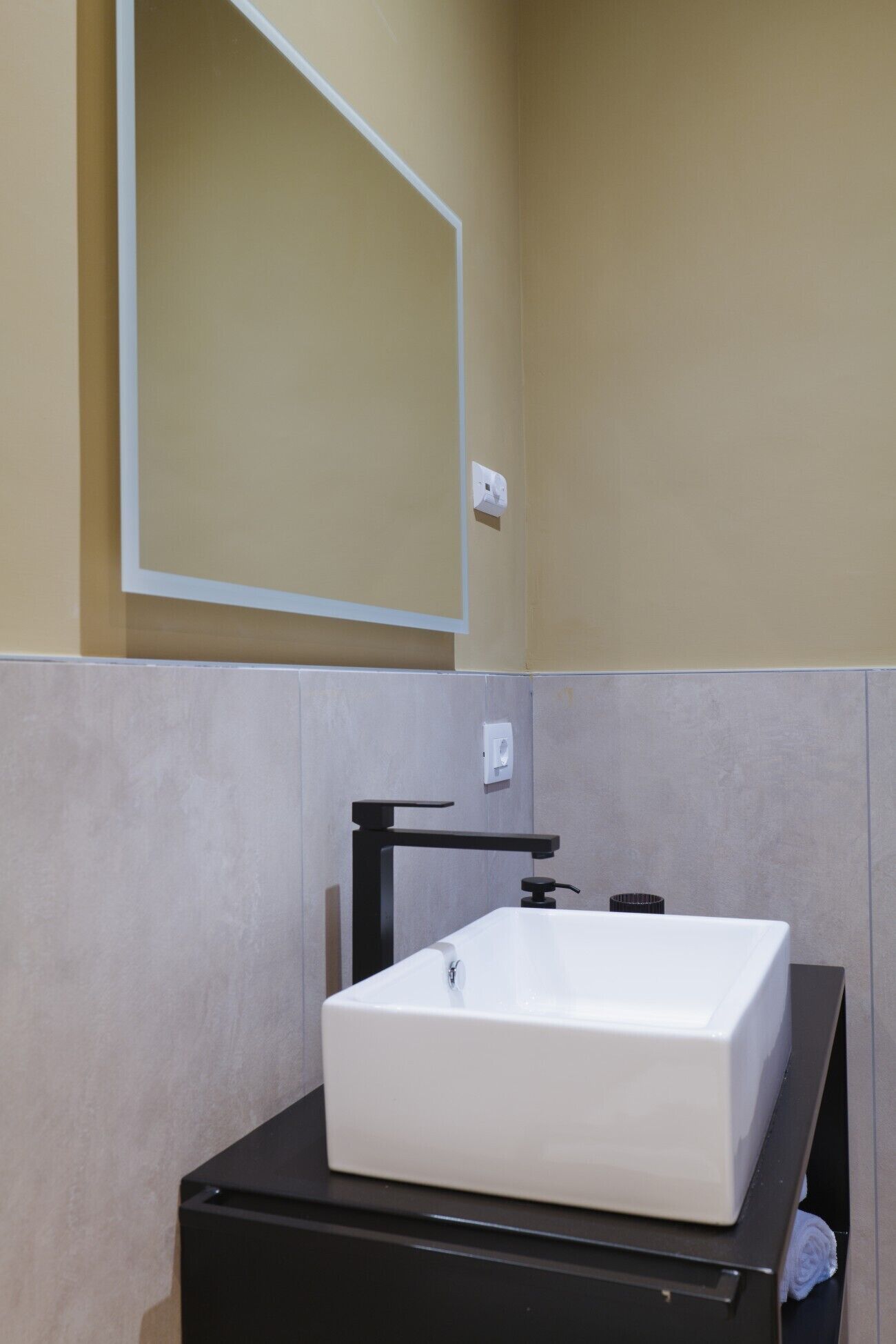 A bathroom with a white rectangular sink, a black faucet, and a mirror above the sink.