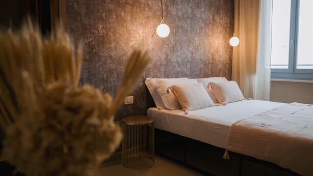 Ein Schlafzimmer mit einem Bett, einem runden Beistelltisch und einer strukturierten Wand.