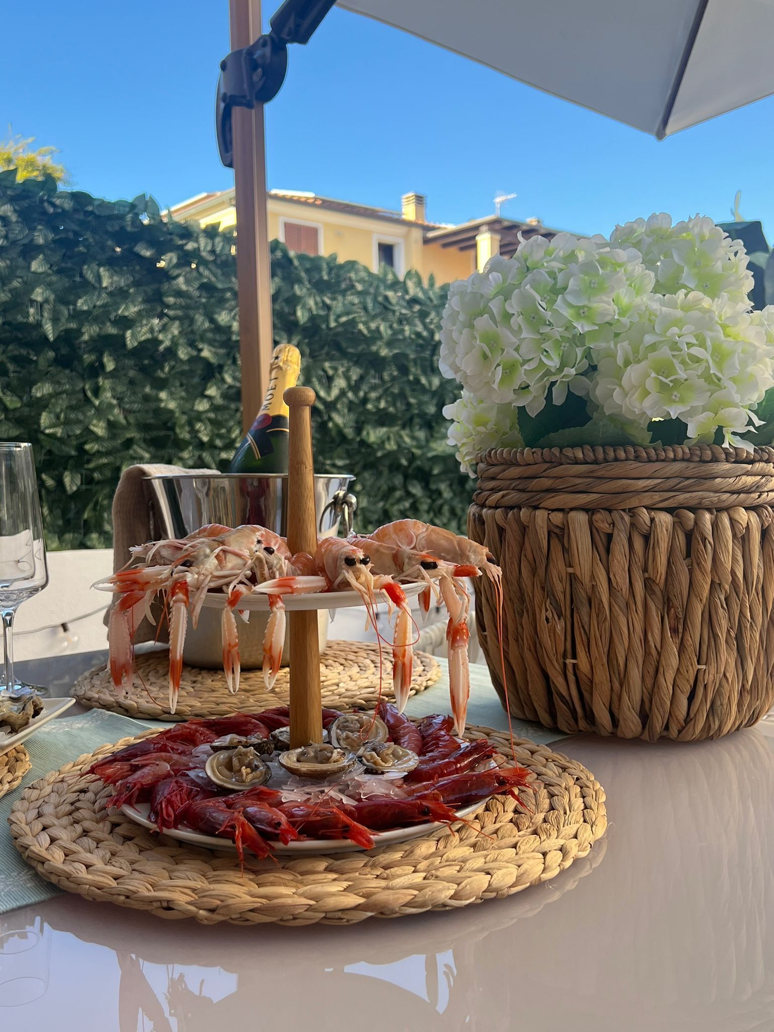 Une table garnie de fruits de mer, une bouteille de champagne et un panier tressé rempli de fleurs.