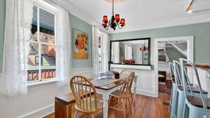 A dining area with a wooden table, chairs, a chandelier, and a fireplace. - Historic High Street Retreat (Harpers Ferry)