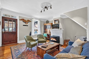 Una sala de estar con chimenea, dos sillones, un sofá y una mesa de centro.
