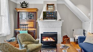 A cozy living room with a fireplace, a wooden cabinet, and a blue sofa. - Historic High Street Retreat (Harpers Ferry)