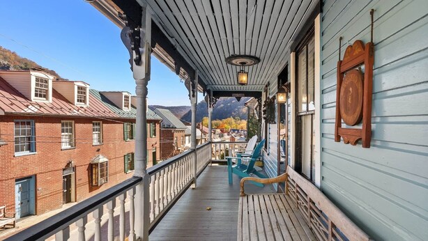 A wooden balcony with a railing, a bench, and a chair. - Historic High Street Retreat (Harpers Ferry)