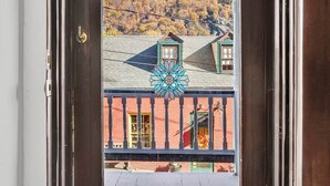 A wooden door with a view of a building with a balcony and a mountain in the background. - Historic High Street Retreat (Harpers Ferry)