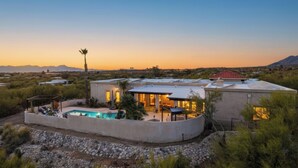 Una casa moderna con piscina, rodeada de vegetación desértica.