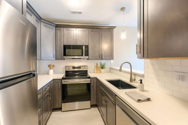 A modern kitchen with stainless steel appliances, a microwave, and a sink.
