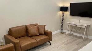 A living room with a brown sofa, a white coffee table, and a TV mounted on the wall.
