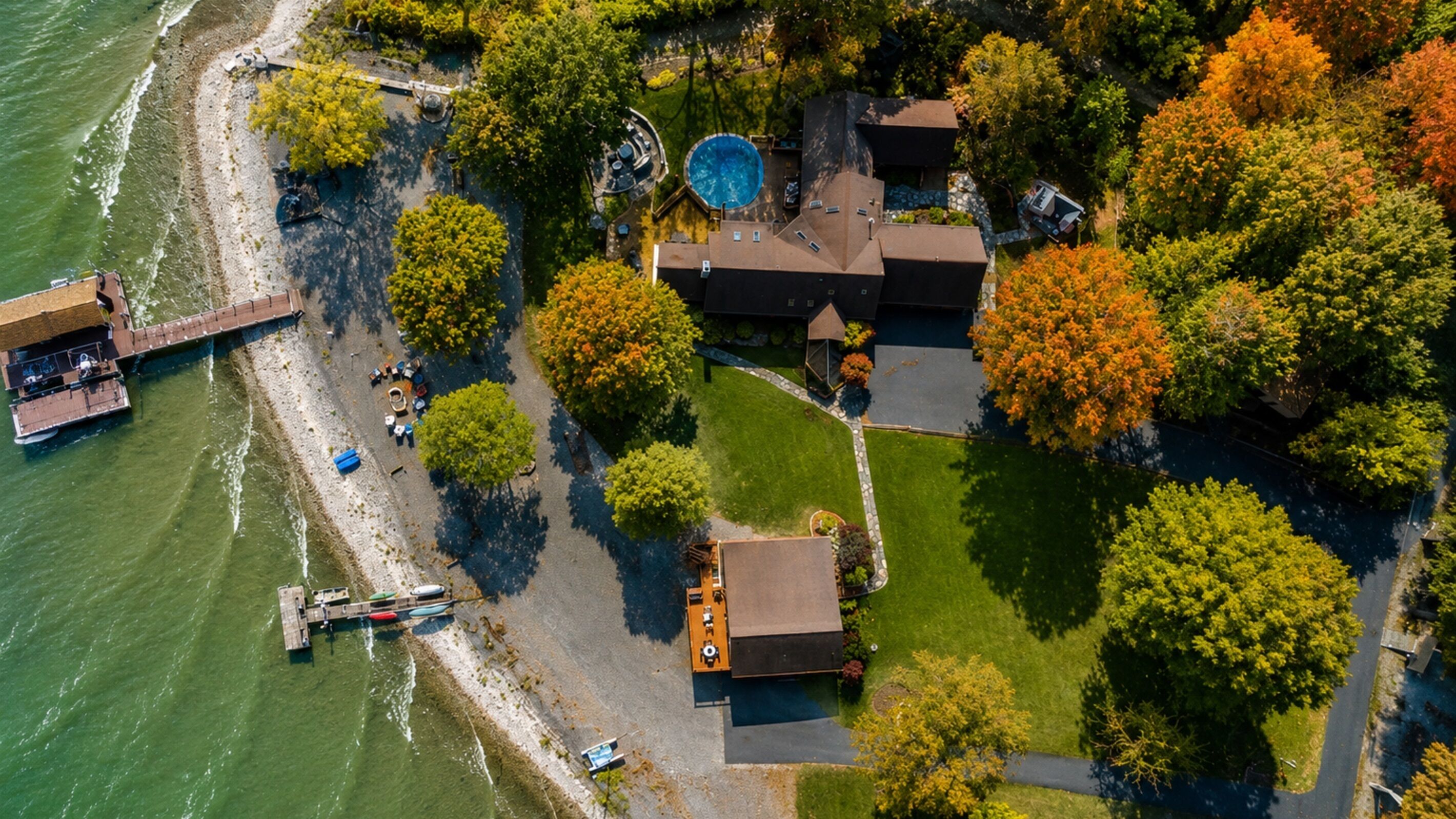 Vue aérienne d’une propriété dotée d’une piscine, d’un quai avec des bateaux et d’une pelouse bien entretenue.