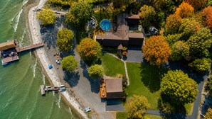 An aerial view of a property with a swimming pool, a dock with boats, and a well-maintained lawn. - Private FLX Retreat | 200' Seneca Lakefront | Pool (Geneva)