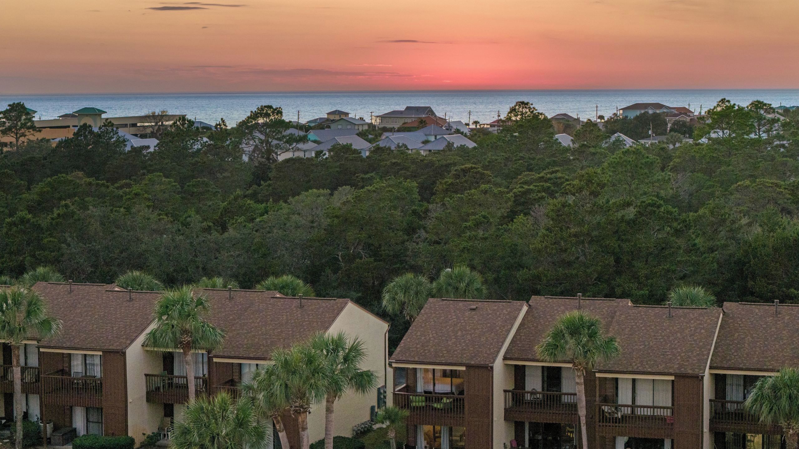 A residential area with houses, a view of the ocean, and a sunset.