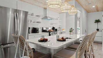 A modern kitchen with a stainless steel refrigerator, a built-in oven, and a large island with seating.