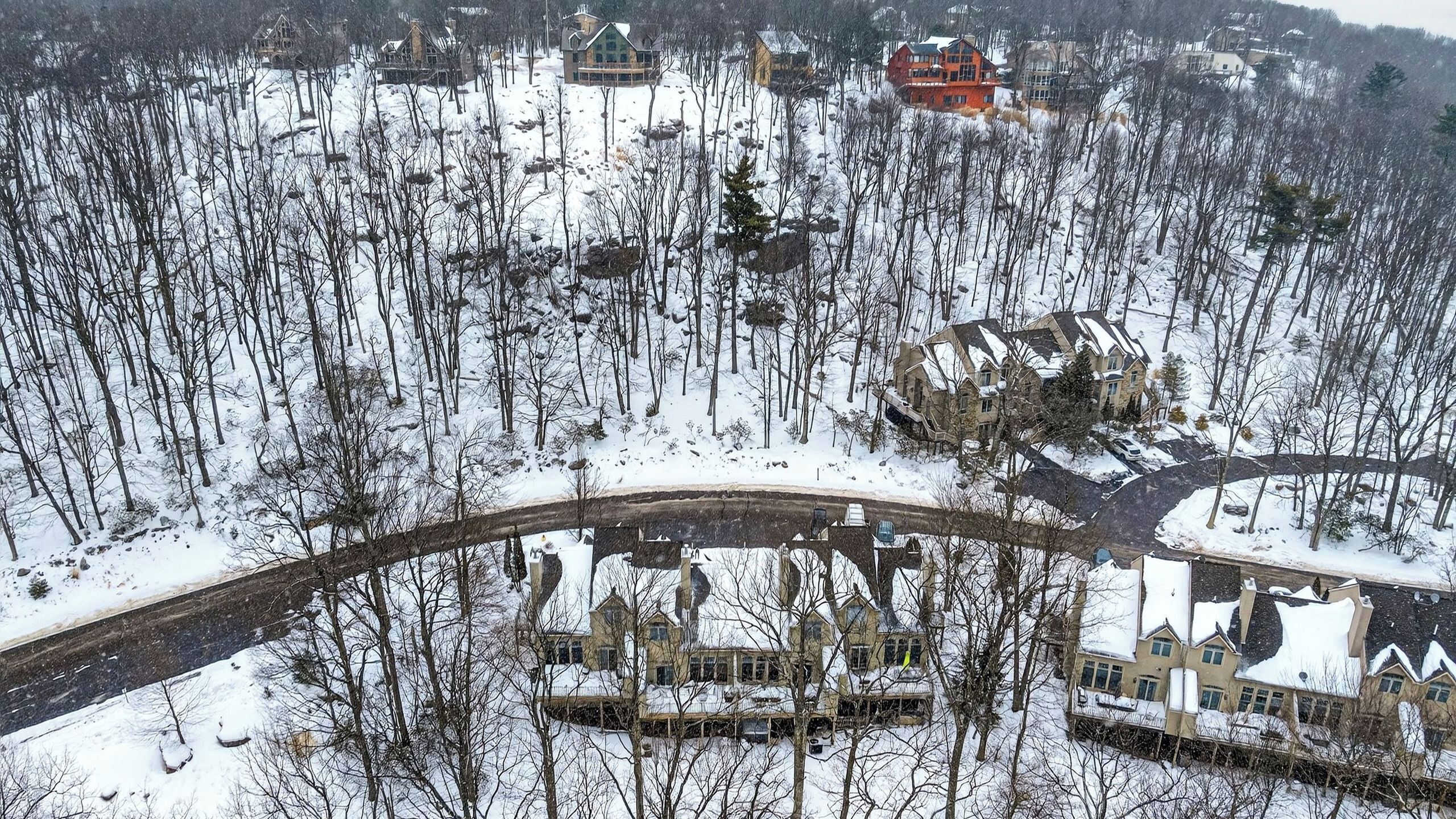 Een besneeuwd landschap met een brug, een groep huizen en een opvallend rood gebouw.
