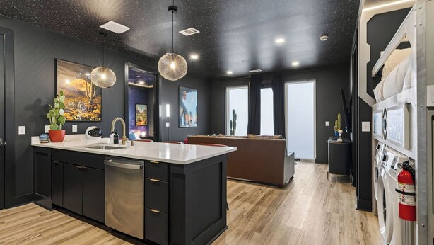 Una cocina moderna con una isla grande, armarios oscuros y piso de madera.