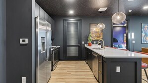 Una cocina moderna con una isla central, electrodomésticos de acero inoxidable y un techo con temática galáctica.